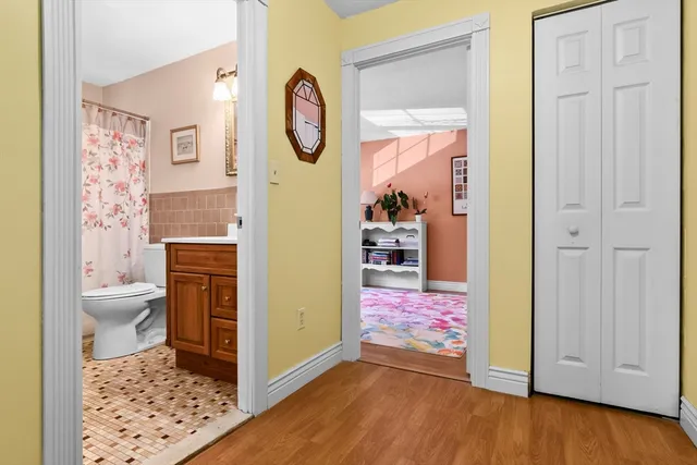 a view of a hallway with bathroom and wooden floor