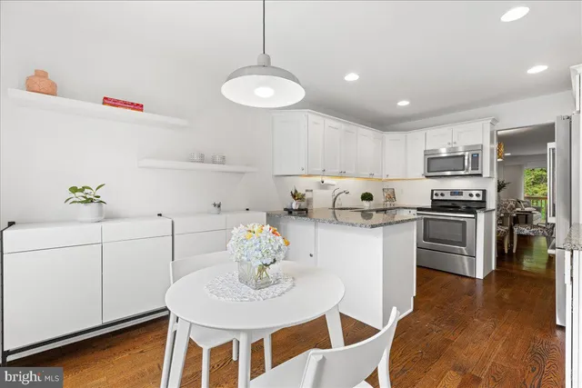 a kitchen with stainless steel appliances granite countertop a sink a stove a dining table and chairs