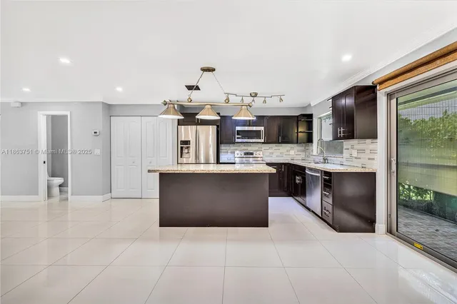 a large kitchen with stainless steel appliances kitchen island granite countertop a sink and cabinets