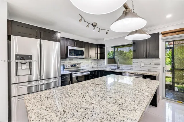 a kitchen with stainless steel appliances granite countertop a sink refrigerator stove and microwave