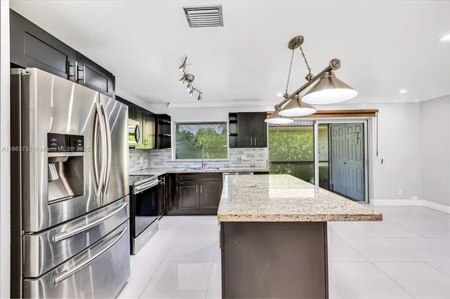 a kitchen with stainless steel appliances granite countertop a refrigerator a sink a stove and a refrigerator