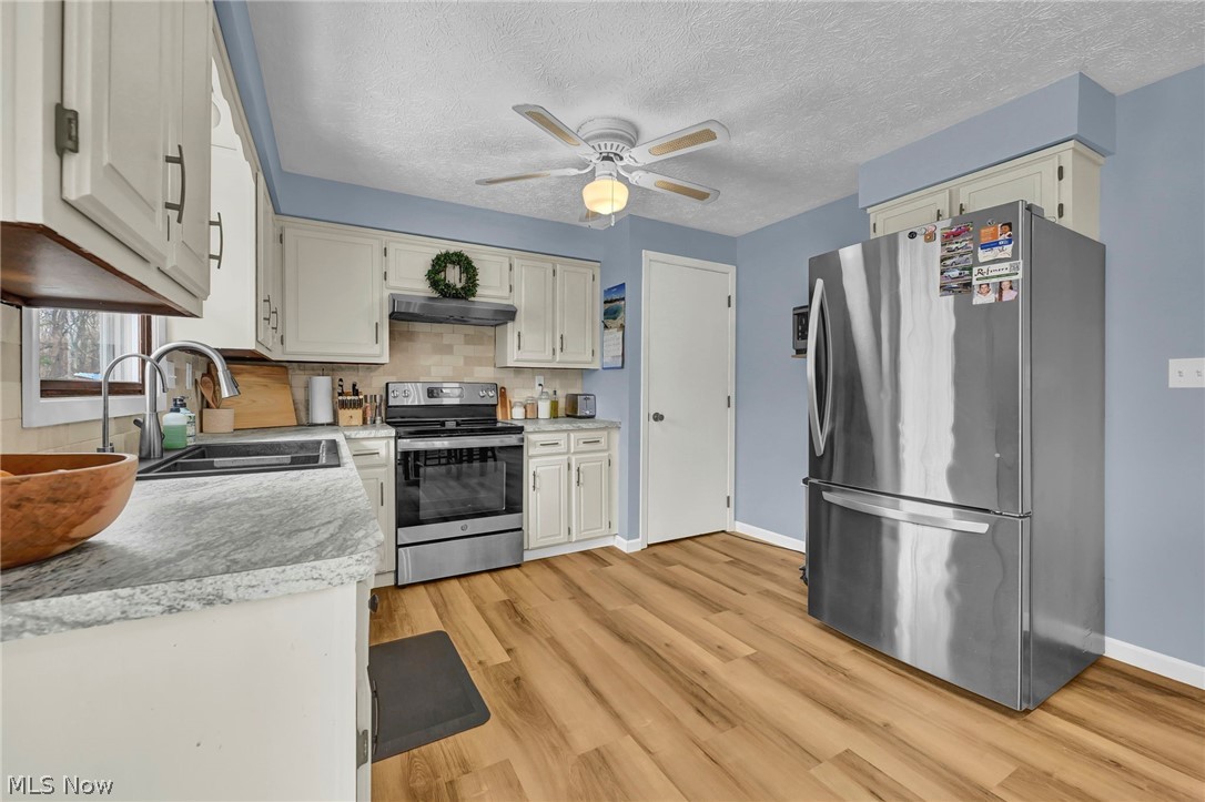 259 East Ohio Avenue Rittman, OH 44270 - Photo 9 of 41 Kitchen featuring light countertops, light wood-style floors, a textured ceiling, and a ceiling fan