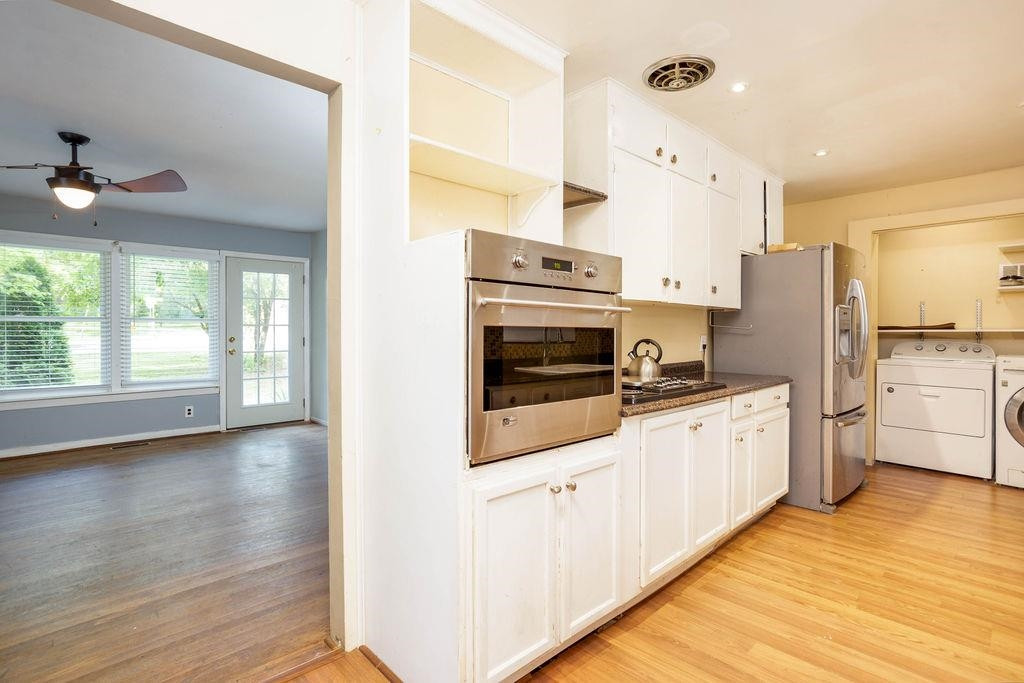 307 South King Charles Road Raleigh, NC 27610 - Photo 5 of 32 a kitchen with stainless steel appliances a stove a sink and white cabinets with wooden floor