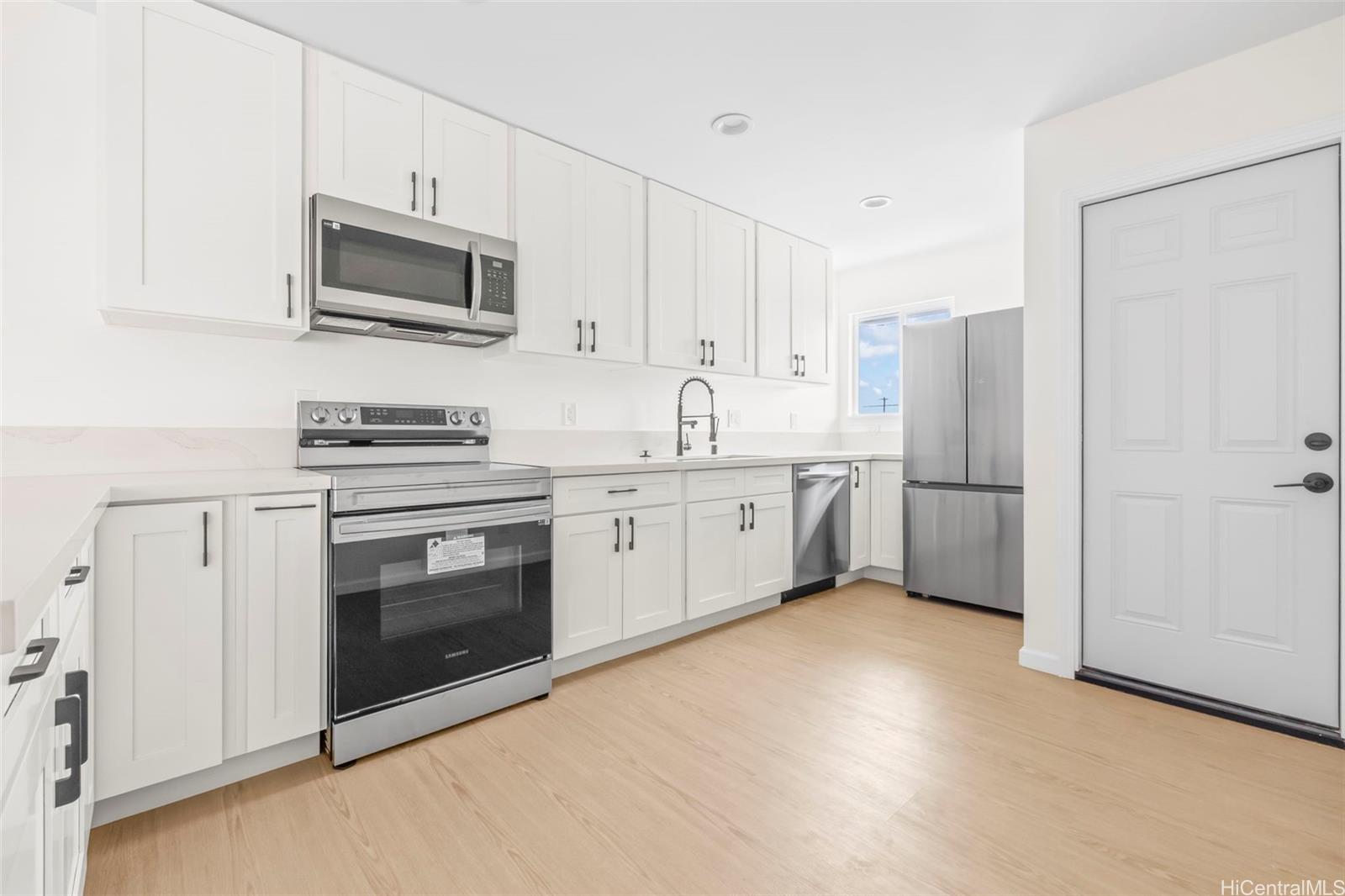 87-1474 Akowai Road, Unit A Waianae, HI 96792 - Photo 24 of 25 a kitchen with stainless steel appliances a white stove top oven a sink and white cabinets