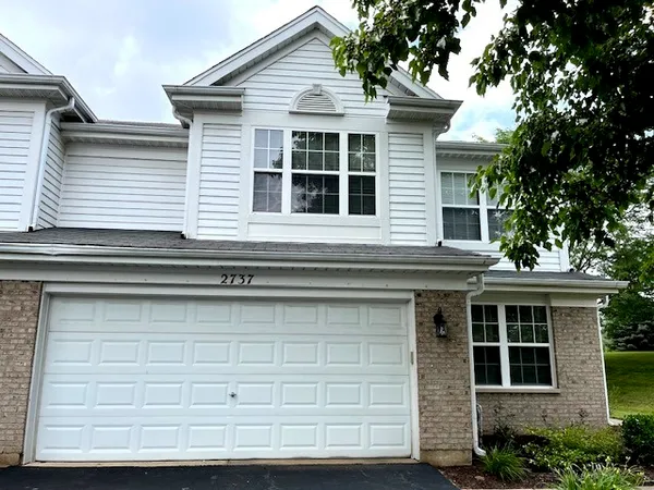 a front view of a house with a tree