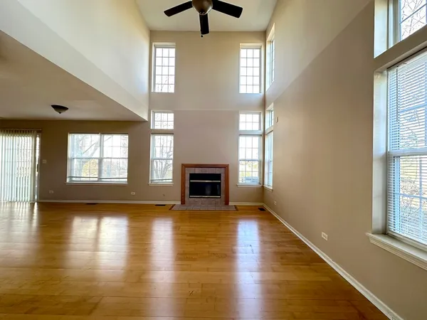 an empty room with wooden floor fireplace and windows
