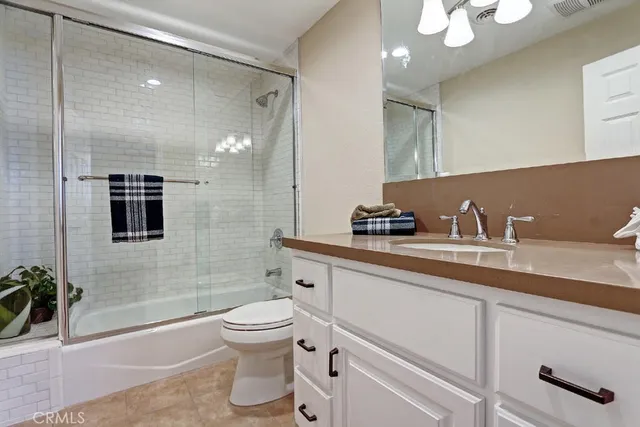 a bathroom with a granite countertop sink a toilet a mirror and shower