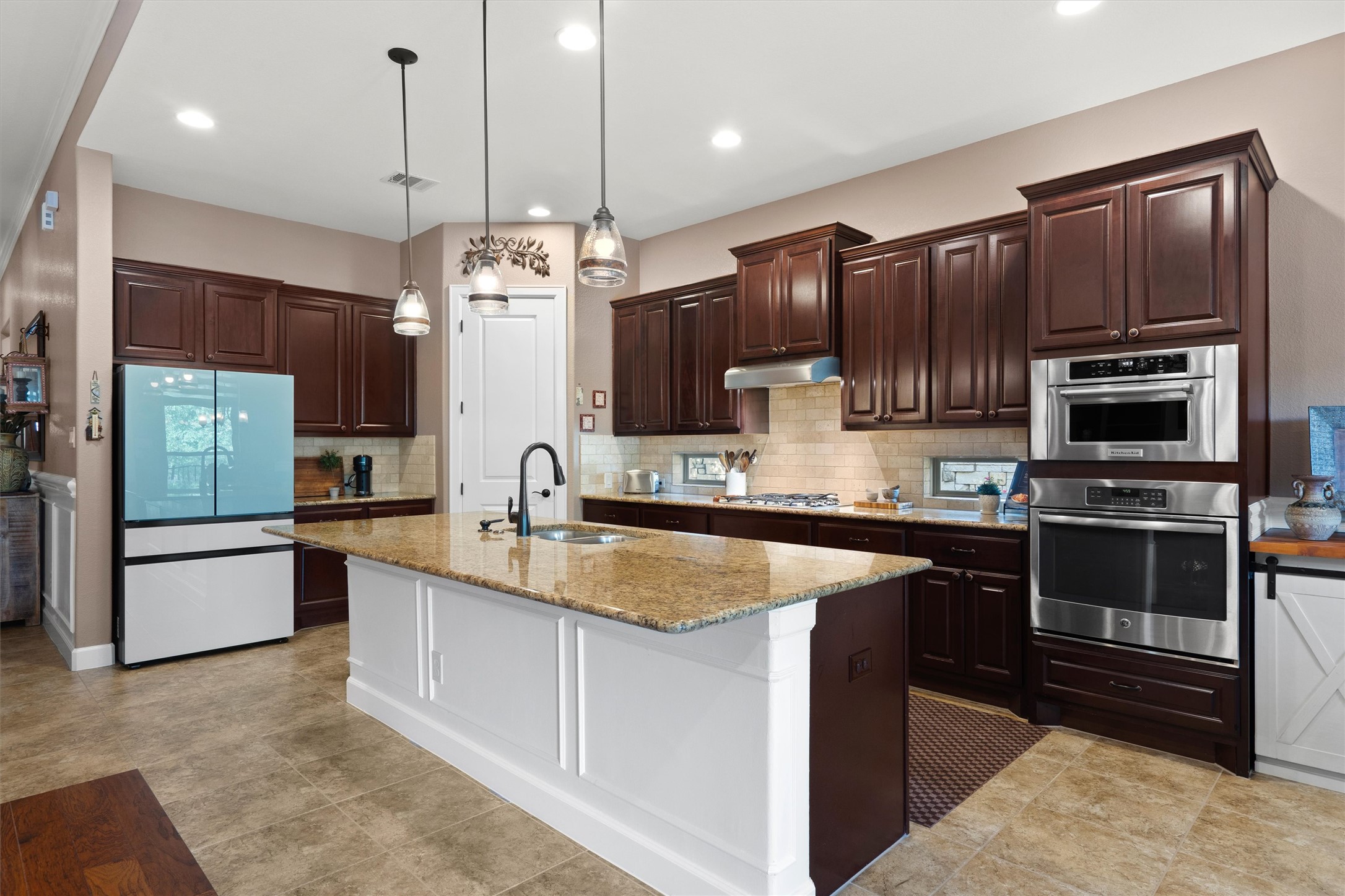 4005 Haight Street Round Rock, TX 78681 - Photo 4 of 40 a large kitchen with stainless steel appliances granite countertop a refrigerator a sink dishwasher a stove with wooden cabinets and floor