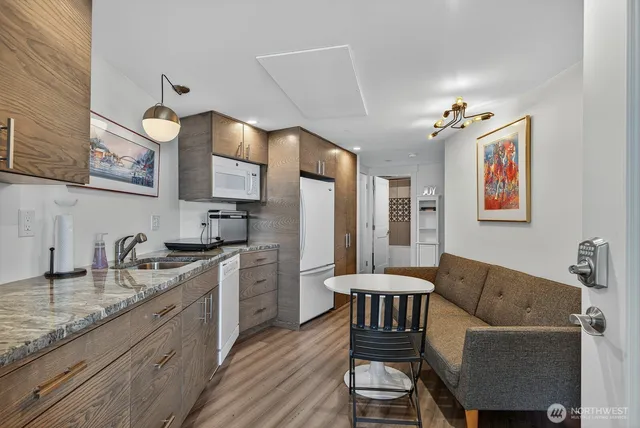 a kitchen with stainless steel appliances granite countertop a sink dishwasher a stove and a refrigerator with wooden floor