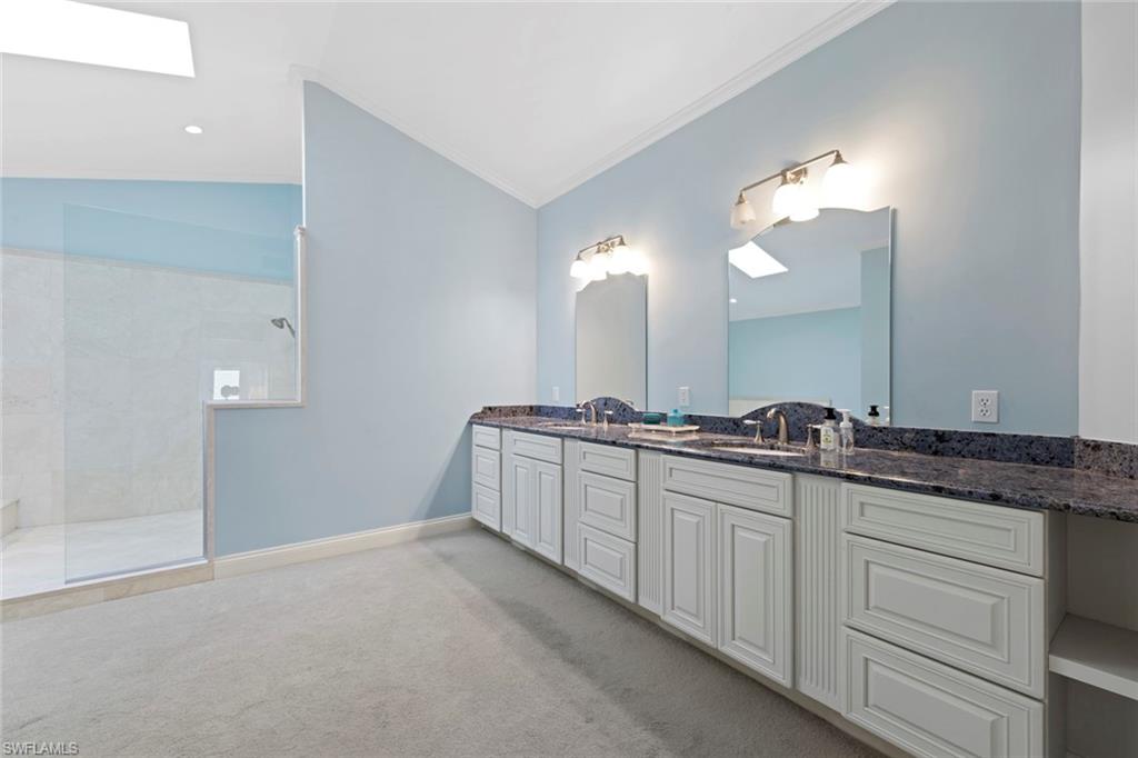 589 Neapolitan Way Naples, FL 34103 - Photo 10 of 27 a bathroom with a double vanity sink and a mirror