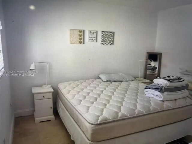 a bedroom with a bed and a lamp on the dresser