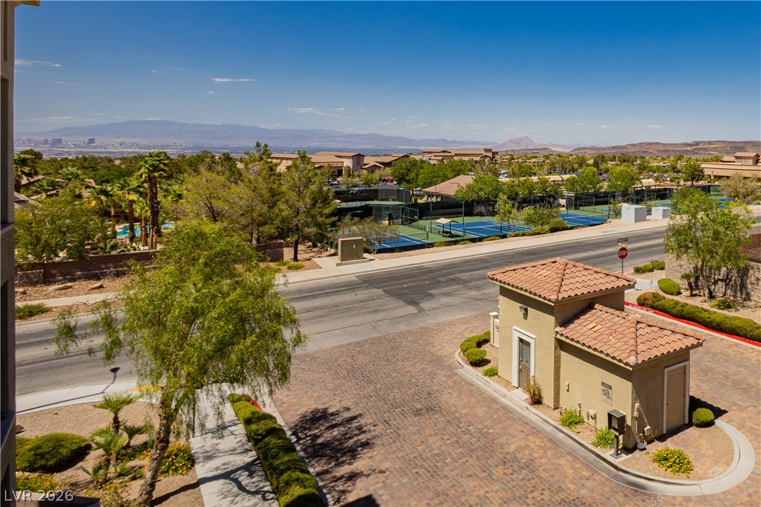 2555 Hampton Road, Unit 3308 Henderson, NV 89052 - Photo 5 of 65 A private community entry with tennis courts nearby, set against a distant mountain backdrop.