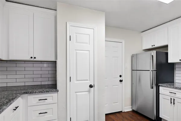 a kitchen with white cabinets and refrigerator