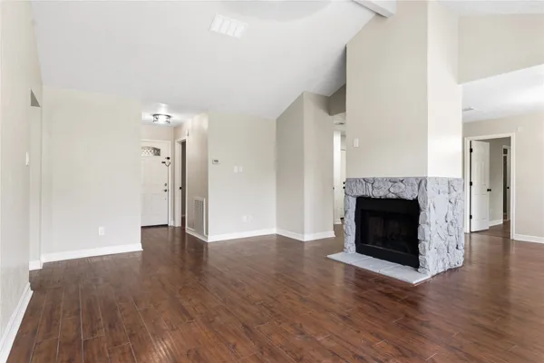 a view of an empty room with wooden floor and a fireplace