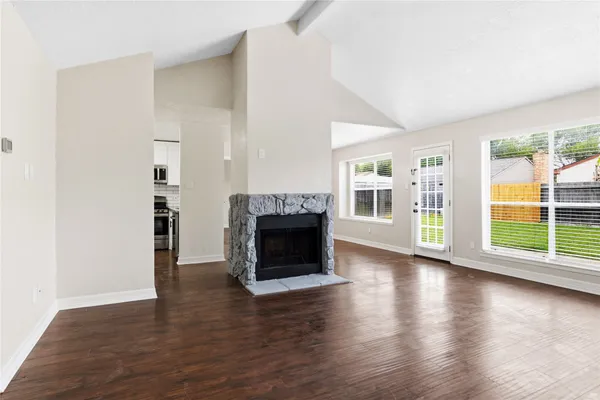 an empty room with floor to ceiling windows and fireplace