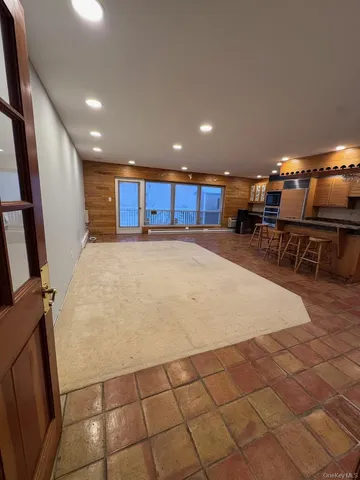 a large white kitchen with stainless steel appliances a sink dishwasher a stove a microwave oven and a dining table with wooden floor