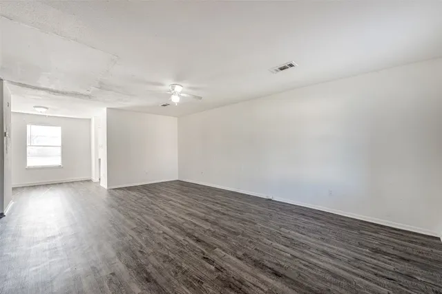 an empty room with wooden floor and window