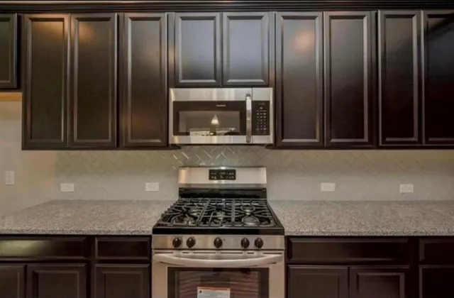 a kitchen with granite countertop stainless steel appliances wooden cabinets and a stove top oven