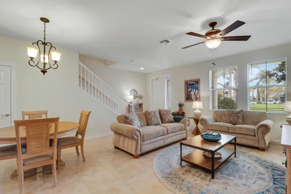 a living room with furniture a two large window and a chandelier