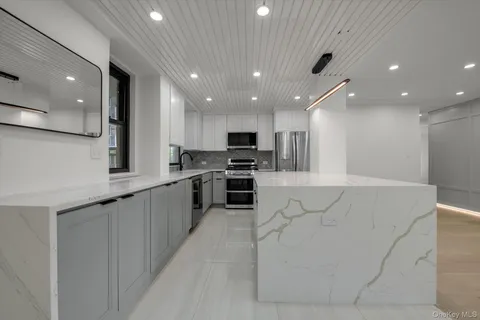 a large kitchen with stainless steel appliances kitchen island granite countertop a large counter top and a stove top oven