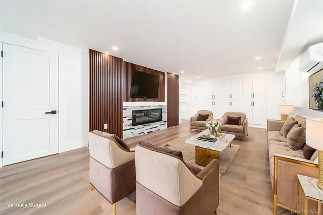 a living room with furniture a flat screen tv and a refrigerator
