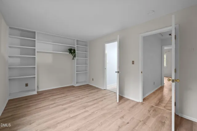 a view of an empty room with closet and a window