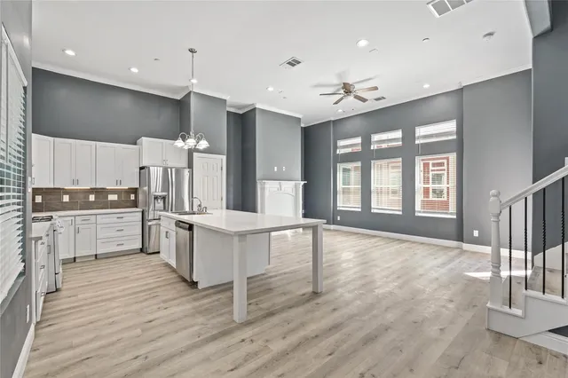 a large white kitchen with wooden floors and white cabinets
