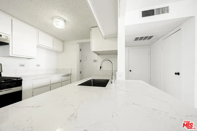 a kitchen with kitchen island a sink a stove and refrigerator