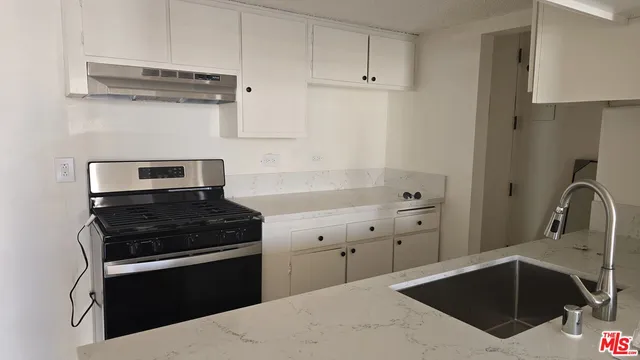 a kitchen with granite countertop a stove sink and cabinets