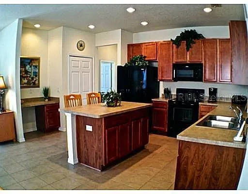 a kitchen with stainless steel appliances kitchen island granite countertop a stove a sink dishwasher and a microwave oven with large wooden cabinets