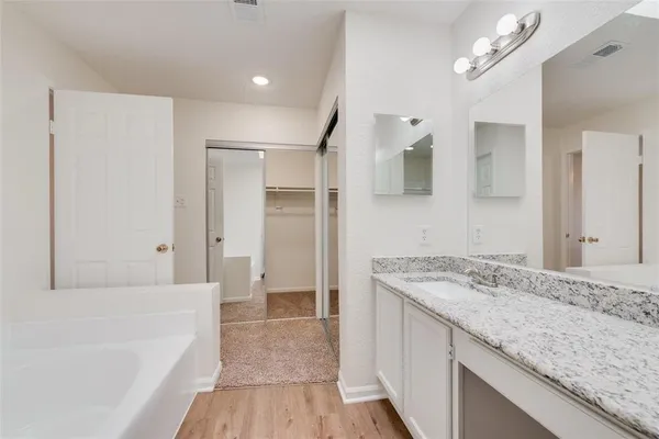 a bathroom with a granite countertop sink a mirror and a bathtub