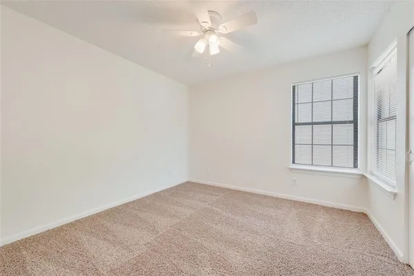 an empty room with a window and a ceiling fan