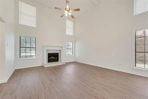 an empty room with wooden floor fireplace and windows