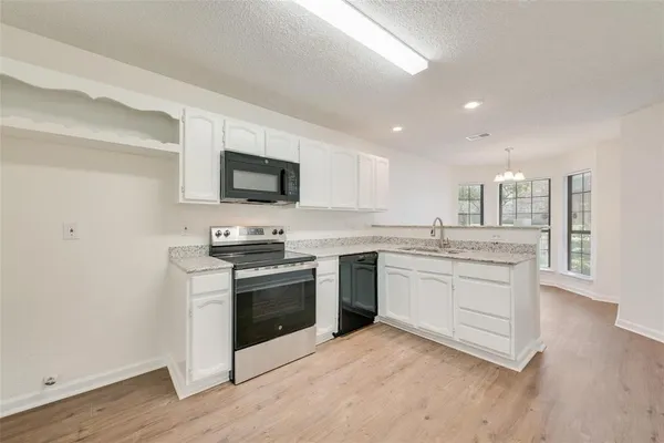 a kitchen with granite countertop white cabinets and stainless steel appliances