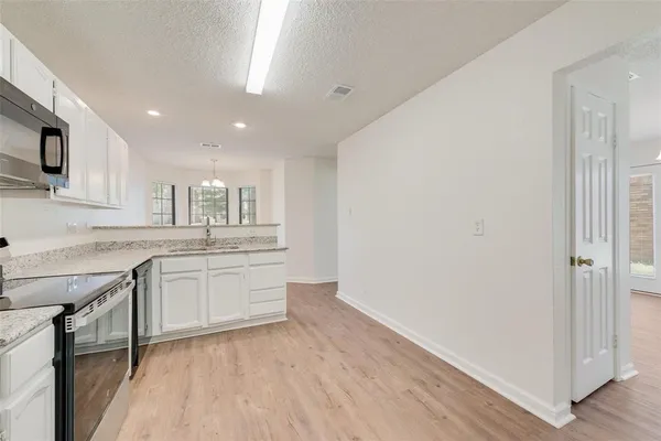a large kitchen with a sink and dishwasher a stove top oven with wooden floor