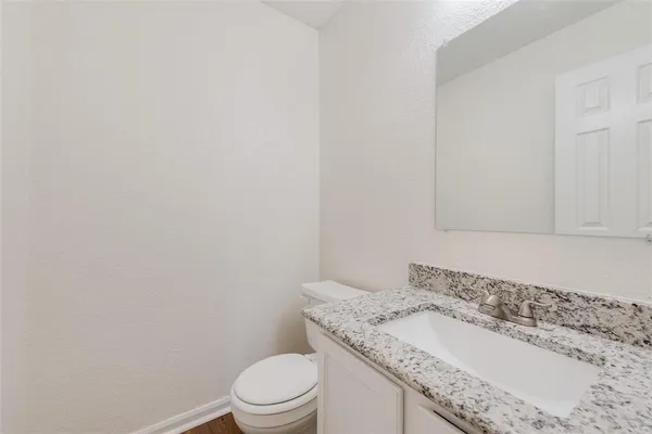 a bathroom with a granite countertop toilet and sink