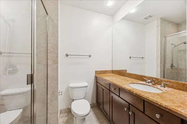 a bathroom with a granite countertop sink a toilet and shower