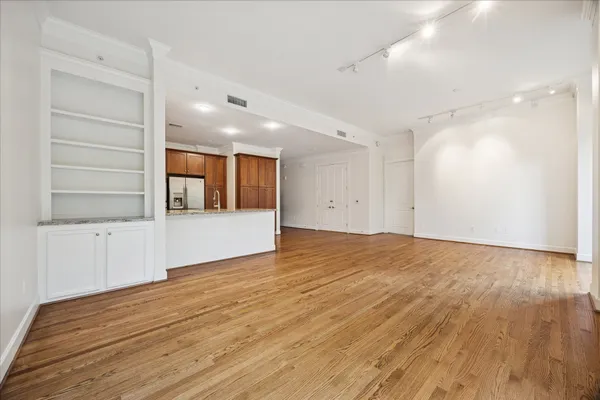 a view of an empty room with wooden floor and windows