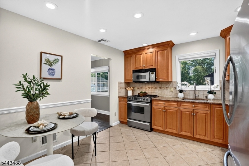 151 East Prospect Street Clark, NJ 07066 - Photo 9 of 31 a kitchen with stainless steel appliances granite countertop a stove a sink dishwasher a dining table and chairs with wooden floor
