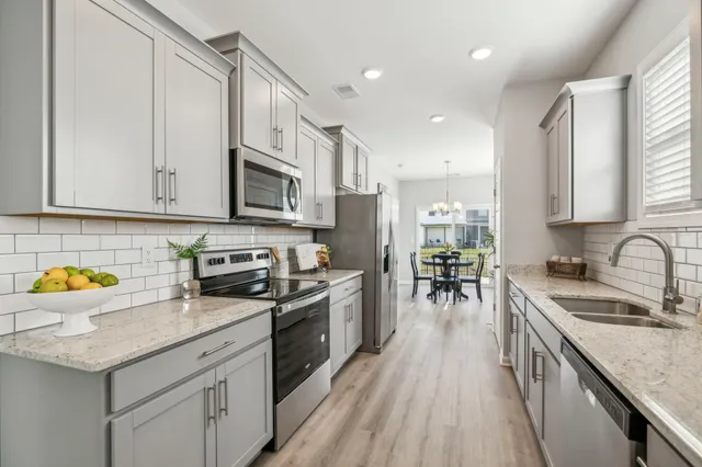 a kitchen with stainless steel appliances granite countertop a stove top oven a sink a dining table and chairs