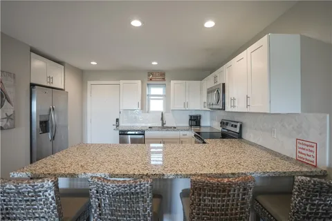 a kitchen with granite countertop kitchen island a sink stainless steel appliances and white cabinets