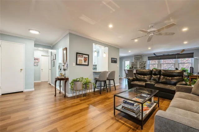 a living room with furniture a wooden floor and a ceiling fan