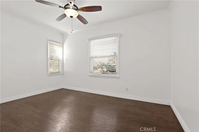an empty room with wooden floor ceiling fan and windows