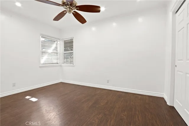 an empty room with wooden floor fan and windows