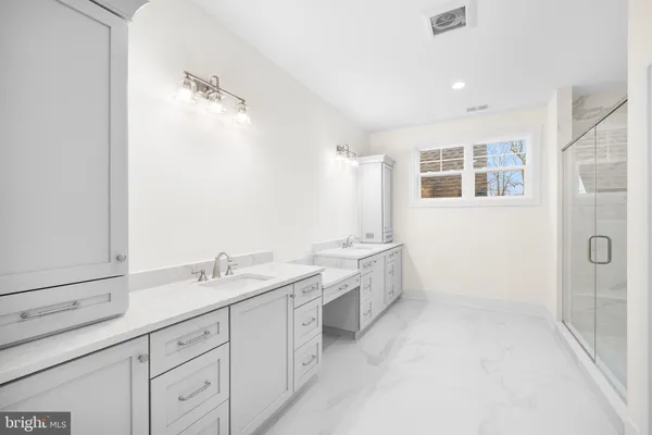 a spacious bathroom with a double vanity sink a mirror and a shower