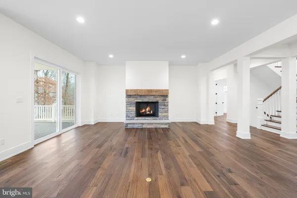 an empty room with wooden floor fireplace and windows