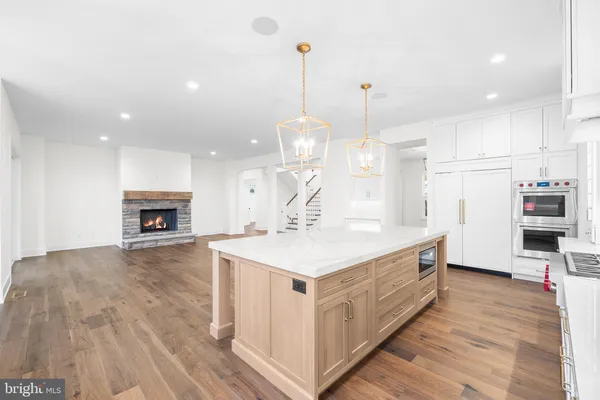 a large white kitchen with a large island oven a stove with wooden floors
