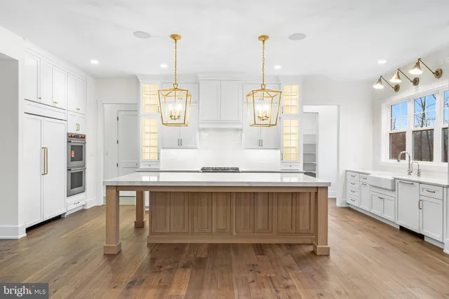 a large kitchen with kitchen island granite countertop a stove a sink and a wooden floors