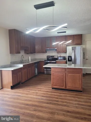 a large kitchen with stainless steel appliances wooden cabinets a sink and a stove