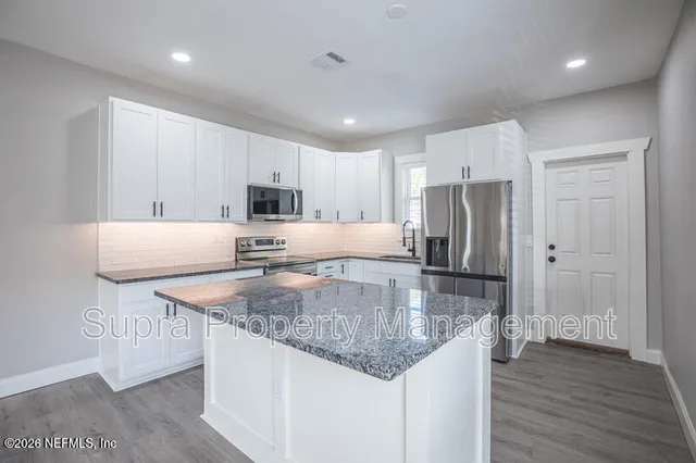a kitchen with stainless steel appliances granite countertop a sink refrigerator and cabinets